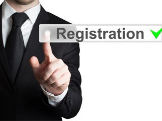 Image of a businessman in black suit pressing button registration isolated.